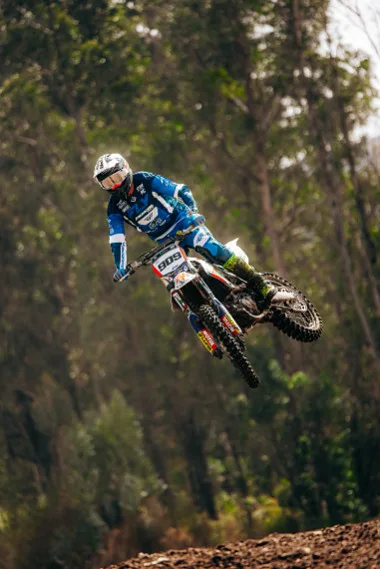 Piloto de azul en pleno salto rodeado de bosque