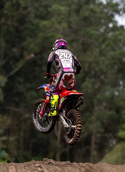 Piloto con moto roja aterrizando tras un salto